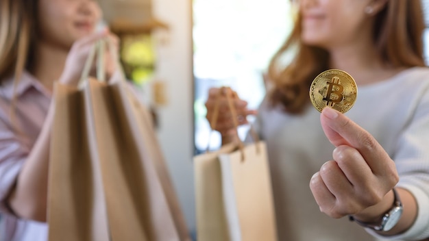 Closeup image of two young women holding and using bitcoin for shopping