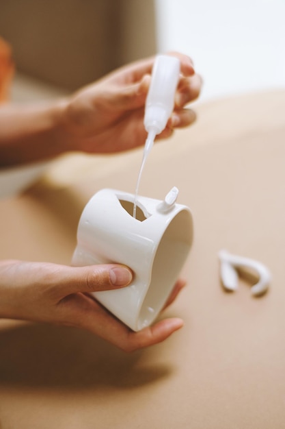 Closeup image of unrecognizable person applying glue on broken tea cup