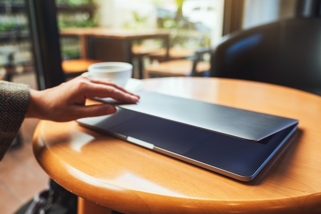 Immagine del primo piano di una donna che chiude e apre un computer portatile sul tavolo dopo aver finito di usarlo