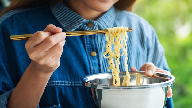 自宅でアジアンスタイルのインスタントラーメンを食べる女性のクローズアップ画像