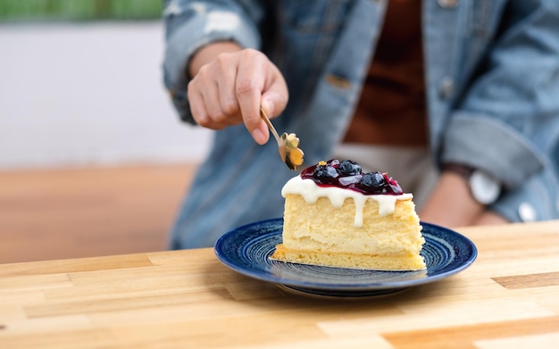 Closeup image of a woman eating blueberry cheesecake with spoon