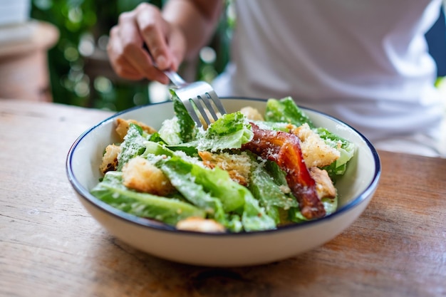 Closeup image of a woman eating a Caesar salad