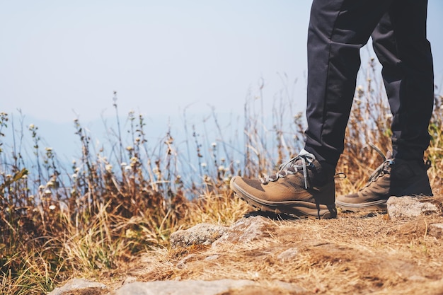 Closeup image of a woman hiking with trekking boots on the top of mountain