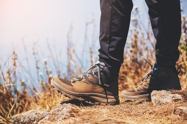 Closeup image of a woman hiking with trekking boots on the top of mountain