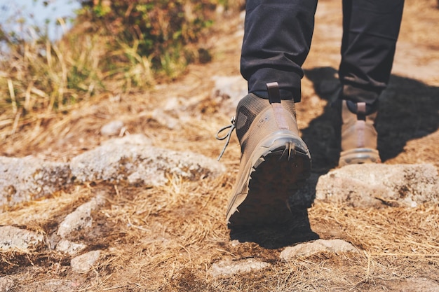 Closeup image of a woman hiking with trekking boots on the top of mountain