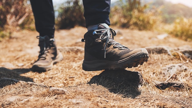 Closeup image of a woman hiking with trekking boots on the top of mountain