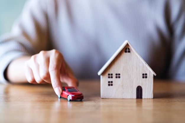 Closeup image of a woman holding and car figure model and wooden house model