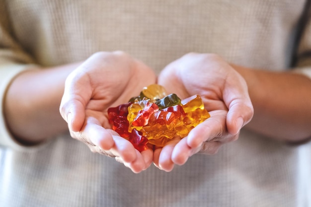 Closeup image of a woman holding colourful jelly gummy bears in hands