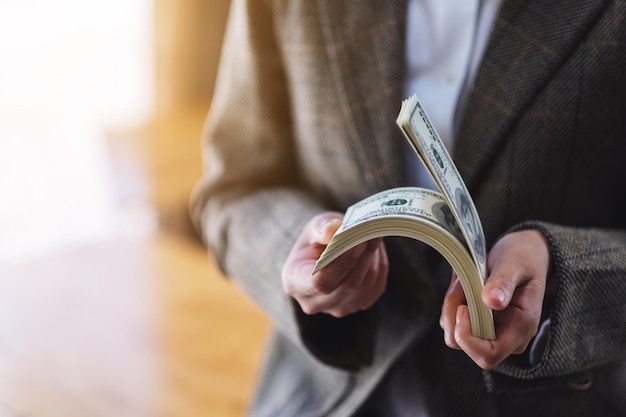 Closeup image of a woman holding and counting American dollar banknotes for money and financial concept