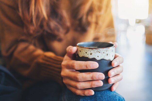 ホットコーヒーのカップを保持している女性のクローズアップ画像