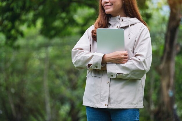 Closeup image of a woman holding a digital tablet in the outdoors