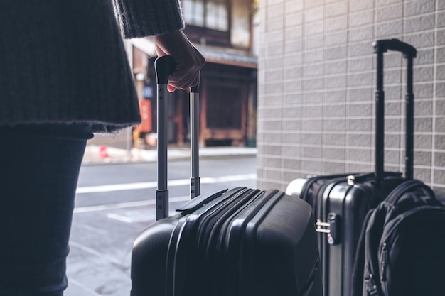 Closeup image of a woman holding and  dragging a black baggage for traveling in the outdoors