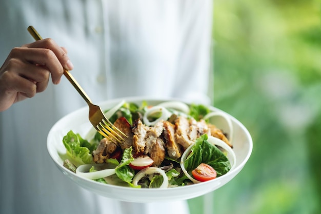 Closeup image of a woman holding and eating chicken salad