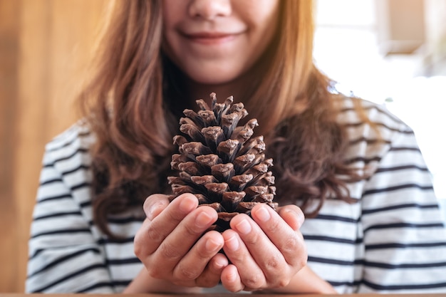 Closeup image of a woman holding a pine cone in her hands