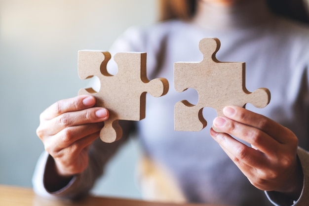 Closeup image of a woman holding and putting a piece of wooden jigsaw puzzle together