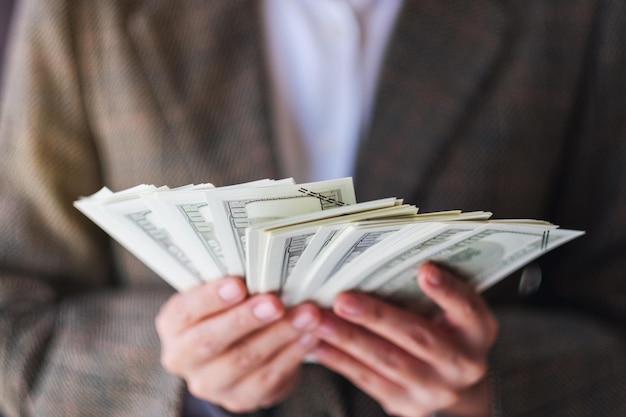 Closeup image of a woman holding and showing American dollar banknotes for money and financial concept