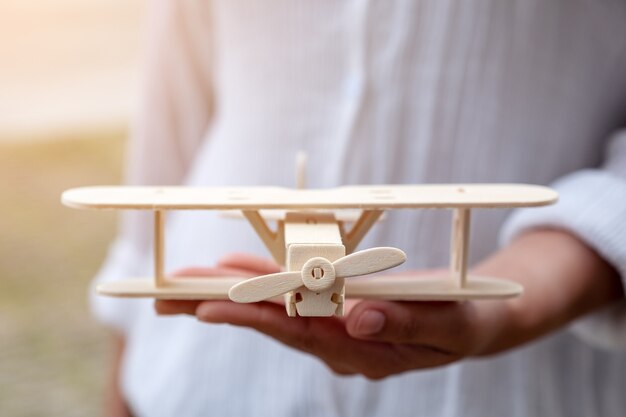 Closeup image of a woman holding and showing a wooden airplane in her hand