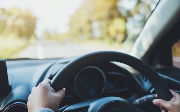 Closeup image of a woman holding steering wheel while driving a car on the road