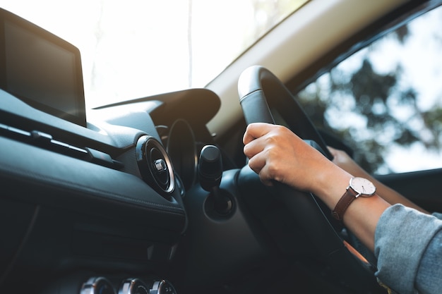 Closeup image of a woman holding steering wheel while driving a car