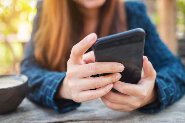 Closeup image of a woman holding and touching on mobile phone screen