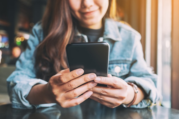 Closeup image of a woman holding , using and looking at mobile phone