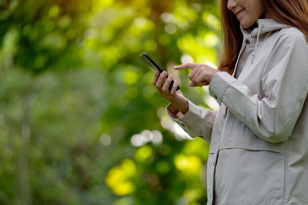 Foto immagine del primo piano di una donna che tiene e utilizza il telefono cellulare in mezzo alla natura