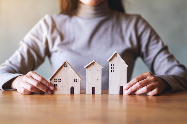 Closeup image of a woman holding wooden house models on the table