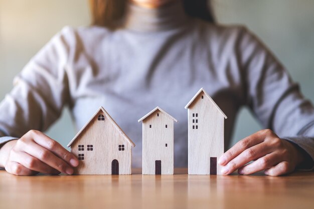 Immagine del primo piano di una donna che tiene i modelli di casa in legno sul tavolo