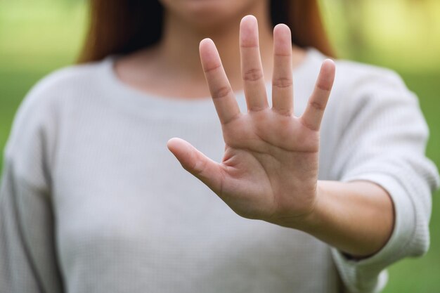 Closeup image of a woman outstretched hand and showing stop hand sign