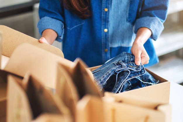 Immagine del primo piano di una donna che riceve e apre una cassetta postale di vestiti a casa per la consegna e il concetto di shopping online