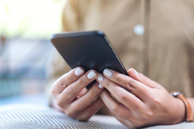 Closeup image of a woman's hands holding and using mobile phone