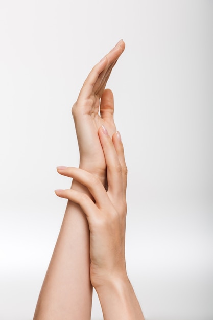 Closeup image of woman's hands isolated over white wall wall touching each other.