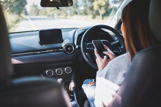 Immagine del primo piano di una donna che usa il cellulare mentre guida un'auto