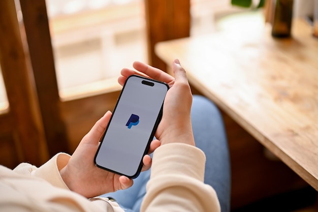 Closeup image of a woman using PayPal on her iPhone PayPal app logo on iPhone screen