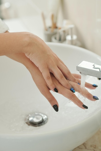 Closeup image of woman washing hands under tap water