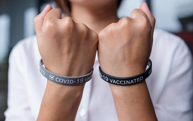 Photo closeup image of a woman wearing and showing covid19 vaccination wristband for health care concept