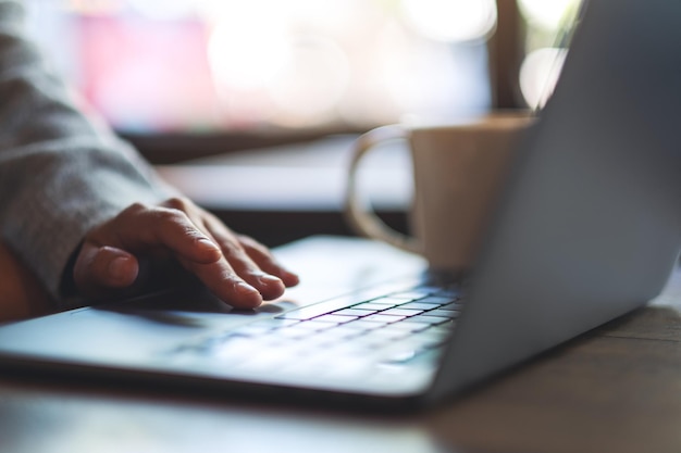 Closeup image of a woman working and touching on laptop computer touchpad on the table