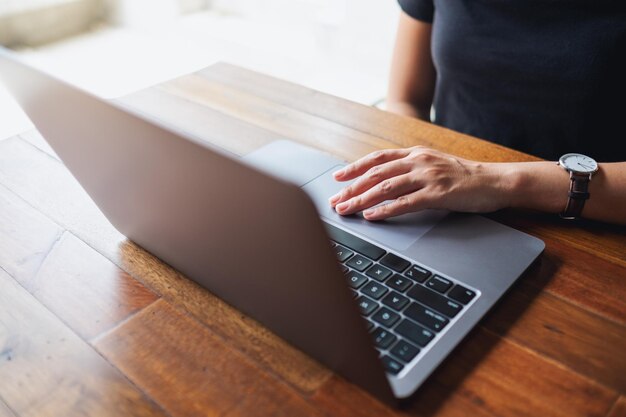 Closeup image of a woman working and touching on laptop touchpad on the table