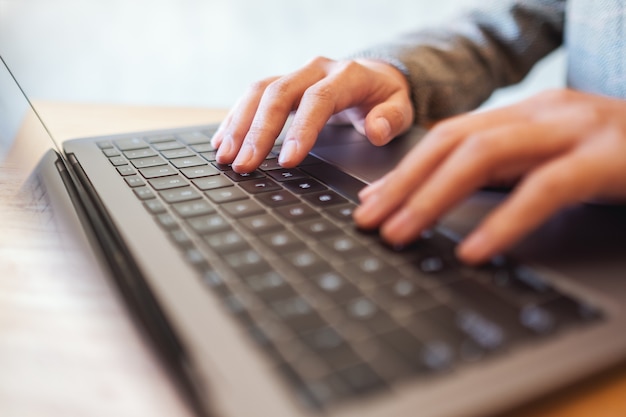 Closeup image of a woman working and typing on laptop computer keyboard on the table