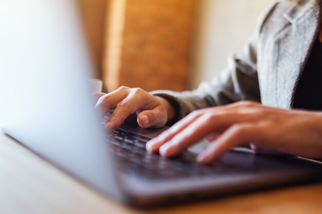 Closeup image of a woman working and typing on laptop computer keyboard on the table