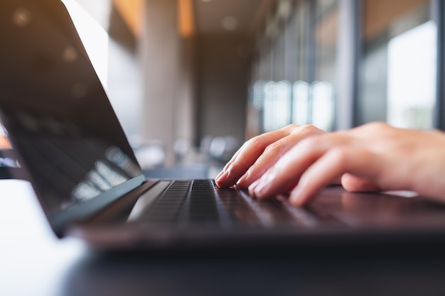 Closeup image of a woman working and typing on laptop computer keyboard on the table