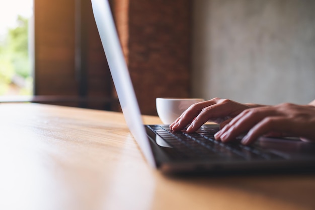 Closeup image of a woman working and typing on laptop computer keyboard on the table