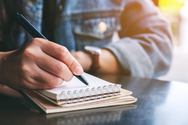 Closeup image of a woman writing on a blank notebook on wooden table