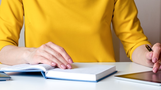 Closeup image of a woman writing down on a white blank notebook