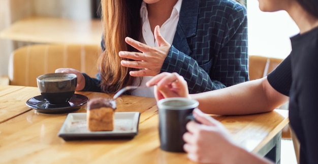 Closeup image of women enjoyed eating dessert and drinking coffee together in cafe