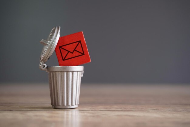 Closeup image of wooden cube with mail icon inside trash can Junk mail and spam mail concept