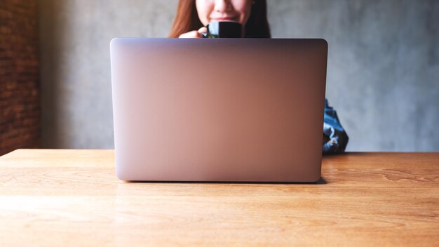 Photo closeup image of a young business woman working on laptop computer on wooden table