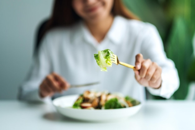 Closeup image of a young woman eating chicken salad on table in the restaurant