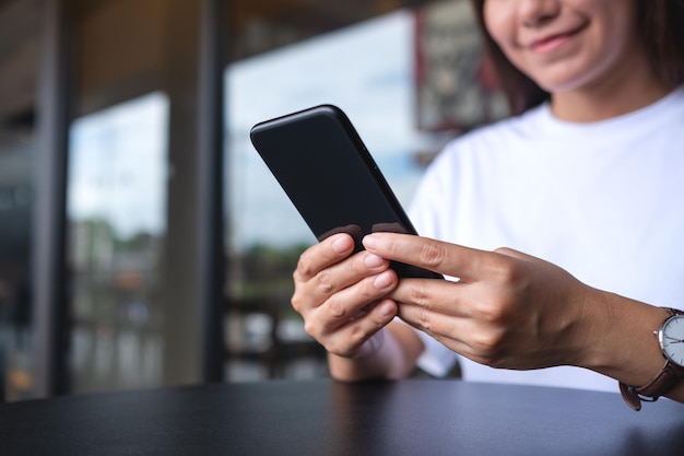 Closeup image of a young woman holding and using mobile phone