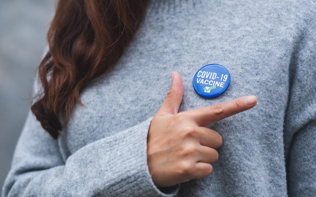 closeup image of a young woman showing covid19 vaccinated sign brooch on shirt